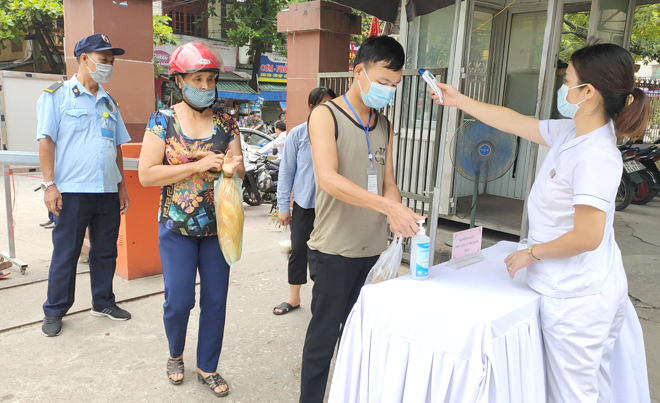 Nhân viên Y tế của Bệnh viện Đa khoa tỉnh Tuyên Quang kiểm tra thân nhiệt của người ra, vào bệnh viện. Ảnh: TL.