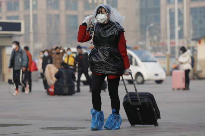 Một hành khách tại nhà ga đường sắt Bắc Kinh che đầu và cơ thể bằng túi nhựa để tăng thêm khả năng bảo vệ chống lại virus Corona. Ảnh: EPA-EFE.