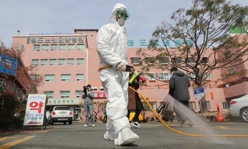 Một nhân viên y tế Hàn Quốc phun thuốc khử trùng trước bệnh viện - nơi có tổng cộng 16 ca nhiễm Covid-19 đã được báo cáo, tại quận Cheongdo gần thành phố Daegu. Ảnh: AFP.