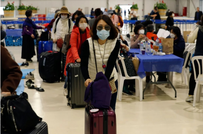 Du khách Hàn Quốc chụp ảnh tại một sân bay trong khi rời Israel vào thứ Hai. Ảnh: AFP.