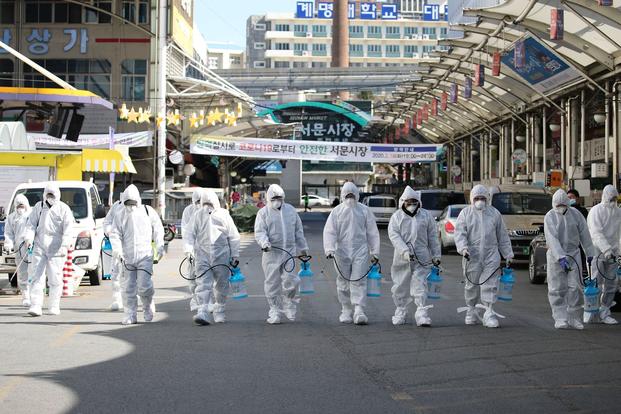Nhân viên y tế mặc đồ bảo hộ phun thuốc khử trùng tại một chợ địa phương ở Daegu (Hàn Quốc). Ảnh: Im Hwa-young/Yonhap.