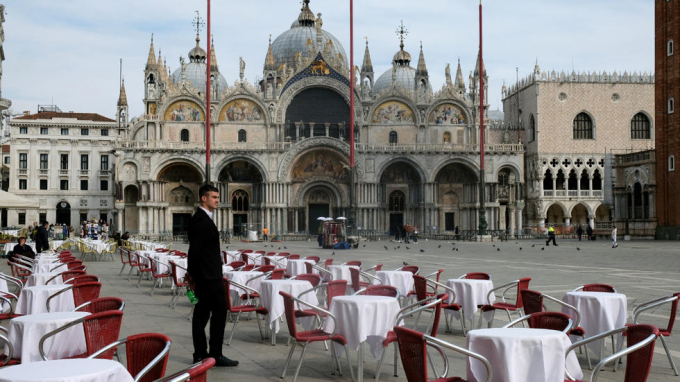 Một người phục vụ đứng cạnh những chiếc bàn trống bên ngoài một nhà hàng tại Quảng trường St Mark (Venice) sau khi chính phủ Italia áp dụng 
