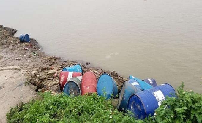 Hàng chục thùng phuy nghi chứa chất độc bị một đối tượng vứt bỏ ra mép sông Hồng, đoạn đi qua xã Vạn Phúc. Ảnh: Quang Vinh.