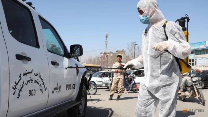 Một nhà hoạt động xã hội dân sự trong bộ đồ bảo vệ phun chất khử trùng lên xe cảnh sát ở Kabul, Afghanistan ngày 18/3/2020. Ảnh: Omar Sobhani/Reuters.