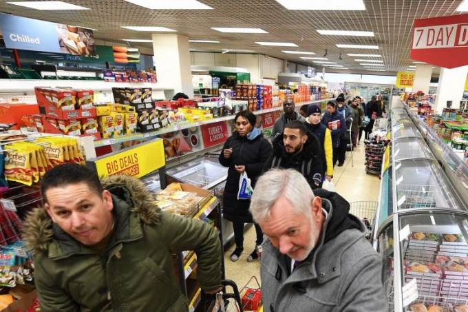 Mọi người xếp hàng tại một siêu thị ở London hôm 19/3/2020. Ảnh: EPA-EFE.