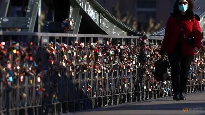 Người phụ nữ đeo khẩu trang đi ngang cầu khóa tình yêu Eiserner Steg, Frankfurt, Đức hôm 23/3/2020. Ảnh: Kai Pfaffenbach/Reuters.