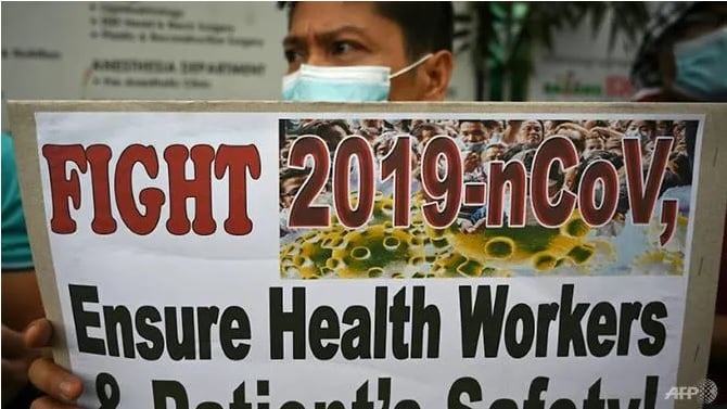 Một nhân viên y tế đeo khẩu trang cầm tấm bảng trong cuộc biểu tình trước Bệnh viện Chính phủ ở Manila. Ảnh: AFP.