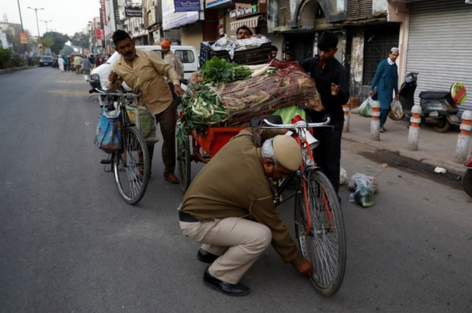 Một cảnh sát xì lốp xe của người bán rau nhằm ngăn người dân ra khỏi chợ. Bộ Y tế Ấn Độ cho biết số ca nhiễm Covid-19 đã tăng lên tới 649 với 13 trường hợp tử vong.