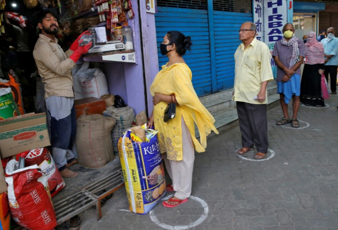 Người dân đứng trong vòng tròn đánh dấu khoảng cách an toàn khi chờ mua thực phẩm.