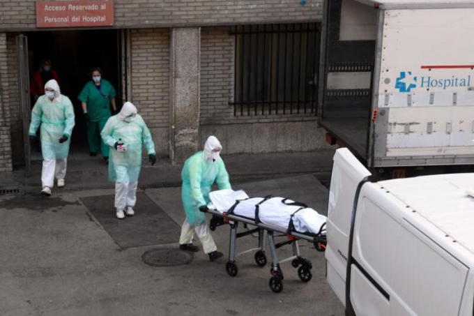 Nhân viên y tế di chuyển xác bệnh nhân mắc Covid-19 bên ngoài bệnh viện ở Madrid hôm 25/3/2020. Ảnh: AFP.