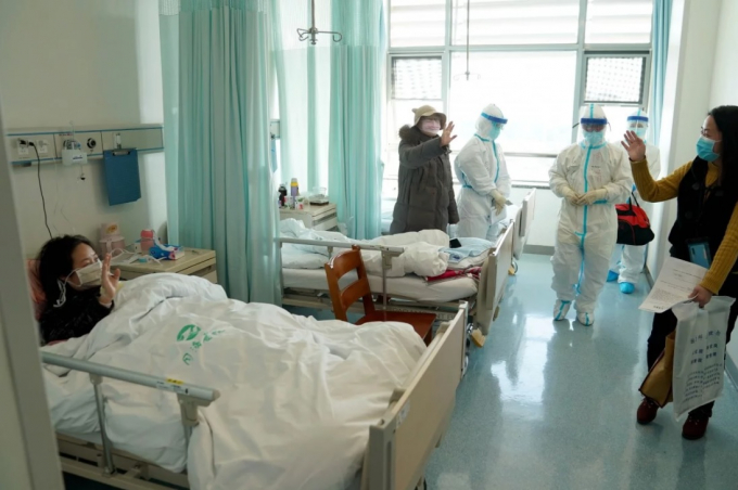 Một người phụ nữ đã hồi phục sau khi mắc Covid-19 nói lời từ biệt với các bệnh nhân cùng phòng tại một bệnh viện ở Vũ Hán. Ảnh: Tân Hoa Xã.
