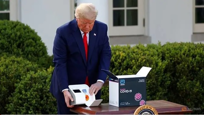 Tổng thống Hoa Kỳ Donald Trump kiểm tra bộ dụng cụ xét nghiệm SARS-CoV-2 khi chuẩn bị phát biểu trong cuộc họp báo về chống đại dịch Covid-19 hàng ngày ở Vườn Hồng tại Nhà Trắng (Washington, Hoa Kỳ) hôm 30/30/2020. Ảnh: Tom Brenner/Reuters.