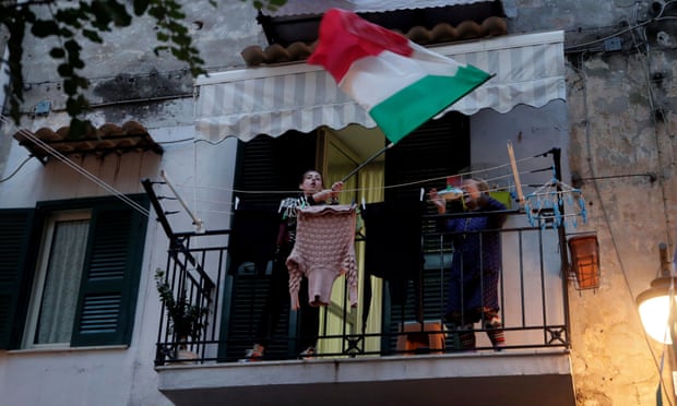 Người phụ nữ vẫy cờ trên ban công ở Napoli trong những ngày đầu sau khi có thông báo phong tỏa. Ảnh: Ciro de Luca/Reuters.
