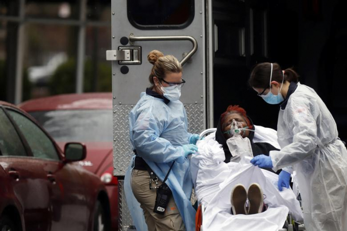 Một bệnh nhân Covid-19 tại New York được y tá hỗ trợ đưa lên xe cứu thương. Ảnh: Reuters.