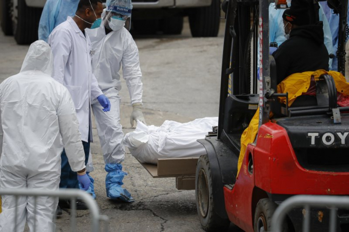 Nhân viên y tế lăn ra một thi thể được bọc bằng nhựa trắng trên cáng và người điều khiển xe cẩn thận nâng lên chiếc xe kéo lạnh tại bệnh viện Brooklyn, quận Brooklyn, New York. Ảnh: AP.