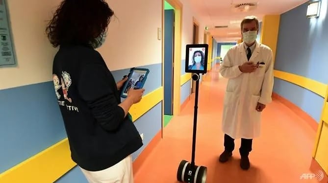 Một y tá (bên trái) vận hành robot để thăm khám bệnh nhân Covid-19 nặng ở Varese, miền bắc Italia. Ảnh: Miguel Medina/AFP.