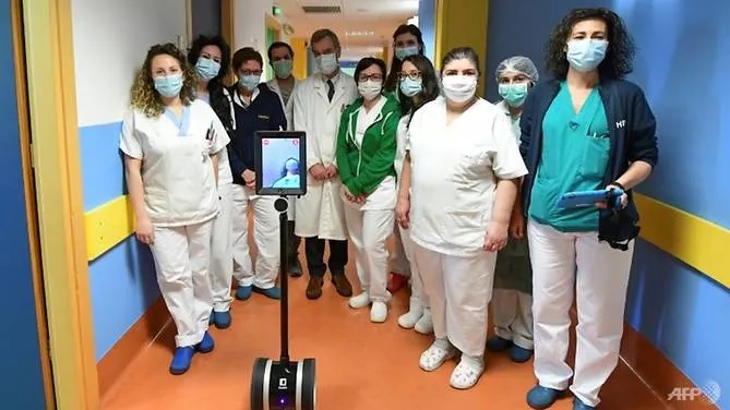 Nhân viên y tế ở Varese, miền Bắc Italia, chụp ảnh với robot IVO, thiết bị giúp họ điều trị bệnh nhân Covid-19 nặng. Ảnh: Miguel Medina/AFP.