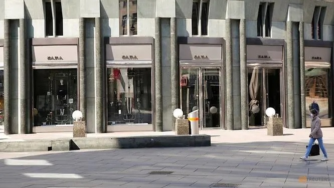 Người phụ nữ đeo khẩu trang đi qua cửa hàng Zara đóng cửa ở Vienna, Áo. Ảnh: Reuters.