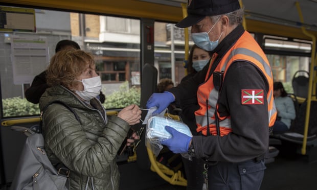 Một tình nguyện viên phát khẩu trang cho hành khách xe buýt ở San Sebastian, Tây Ban Nha. Ảnh: Gari Garaialde/Getty Images.