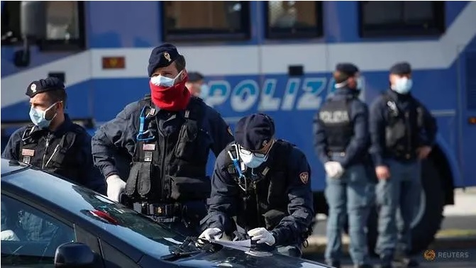 Sĩ quan cảnh sát đeo khẩu trang bảo vệ kiểm tra tài liệu của các tài xế ở Ostia, gần Rome, Italia. Ảnh: Reuters.