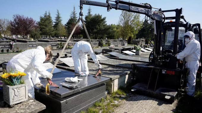 Công nhân thành phố mặc đồ bảo hộ bịt kín mộ của nạn nhân bị Covid-19 tại nghĩa trang El Salvador ở Vitoria, Tây Ban Nha, ngày 27/3/2020. Ảnh: Reuters.
