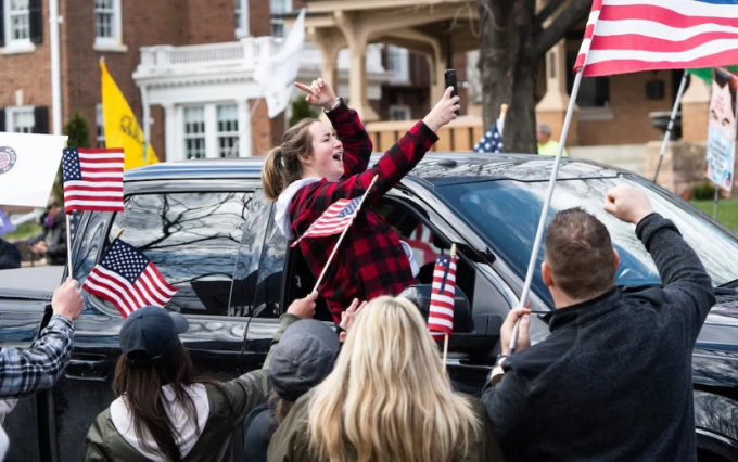 Người phụ nữ dựa vào cửa sổ xe để chụp ảnh selfie với những người biểu tình trong cuộc kêu gọi 'Giải phóng Minnesota'. Ảnh: Telegraph.