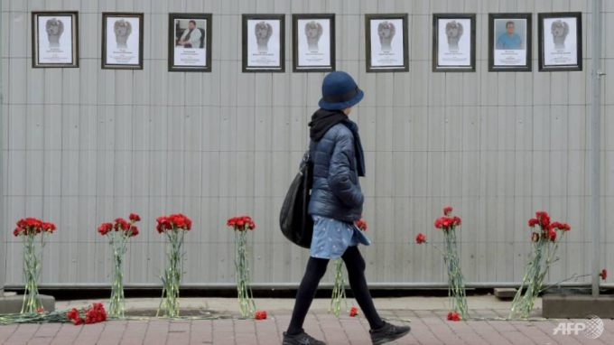 Người phụ nữ đi ngang qua đài tưởng niệm tạm thời cho các nhân viên y tế Nga chết vì Covid-19, được thành lập bên ngoài Sở Y tế địa phương Saint Petersburg. Ảnh: AFP.