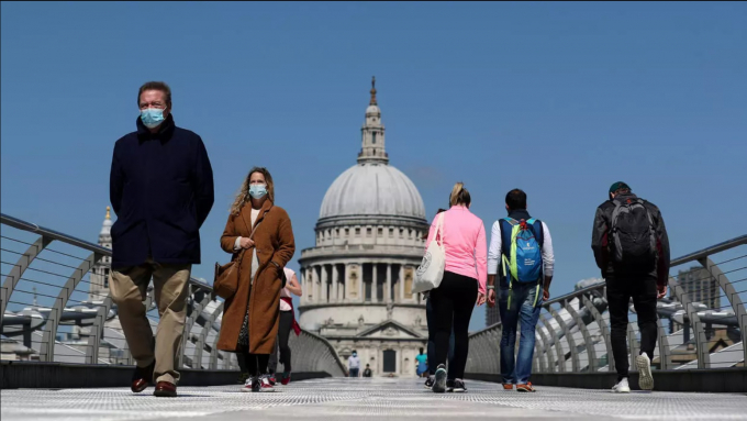 Những người đeo khẩu trang đi qua cầu Thiên niên kỷ, London, Anh, ngày 25/4/2020. Ảnh: Reuters.
