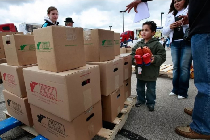 Kevin Estrada, 5 tuổi, đi bộ cùng đống đồ cứu trợ mà gia đình cậu bé nhận được tại một địa điểm phân phối do Feed The Children tổ chức vào ngày 9/5/2009 tại Hoffman Estates, Illinois. Ảnh: Getty Images.