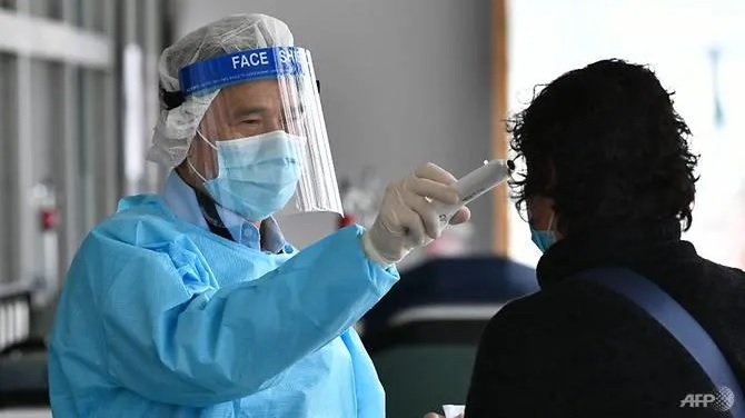 Nhân viên y tế mặc đồ bảo hộ lấy nhiệt độ của một người phụ nữ tại Bệnh viện Princess Margaret ở Hồng Kông ngày 4/2/2020. Ảnh: AFP.