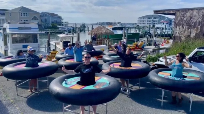 Các nhân viên công ty Revolution Events và nhà hàng Fish Tails Restaurant đi dạo trên phố cầu tàu ở Ocean City, Maryland để giới thiệu khách hàng quen về cách thức giãn cách xã hội mới và thú vị. Ảnh: Newsweek.