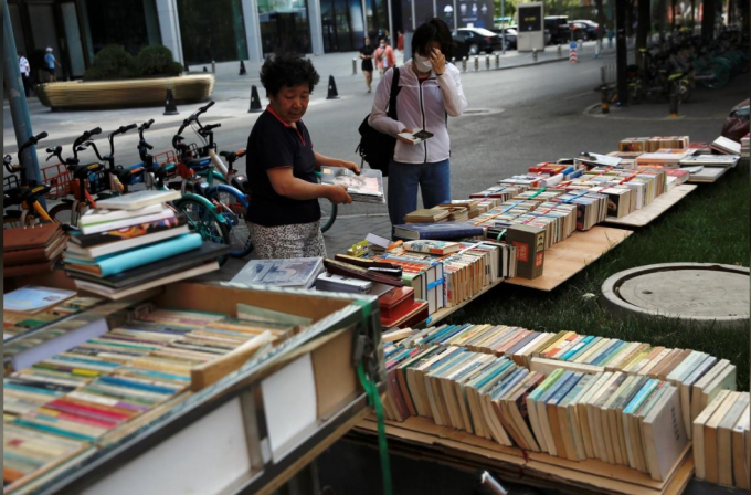Một người bán hàng rong sắp xếp sách tại quầy hàng của bà ở khu mua sắm Sanlitun, Bắc Kinh, Trung Quốc, ngày 5/6/2020. Ảnh: Reuters.