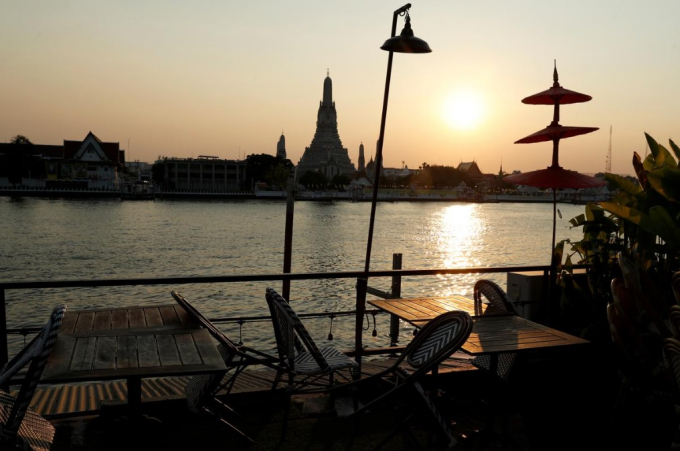 Một nhà hàng đóng cửa do dịch coronavirus (COVID-19) bùng phát, được nhìn thấy bên cạnh sông Chao Phraya với cảnh đền Wat Arun, một trong những điểm du lịch hàng đầu của Bangkok, Thái Lan, ngày 27/3/2020. Ảnh: Reuters.