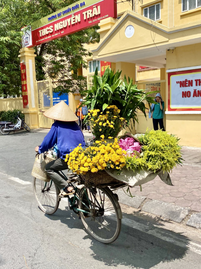 Người phụ nữ đạp xe bán hoa rong ruổi khắp mặt phố Hà Nội lúc 1 giờ chiều. Ảnh: Hoài Trang.
