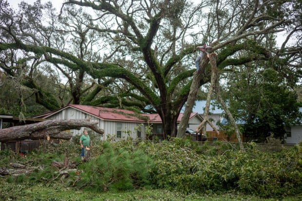 Tony Beritiech, ở Đảo Dauphin, Alabama, theo dõi con trai mình là Matt Beritiech, ở Ocean Springs, dọn dẹp một cái cây bị bão đốn hạ trước nhà. Ảnh: Reuters.