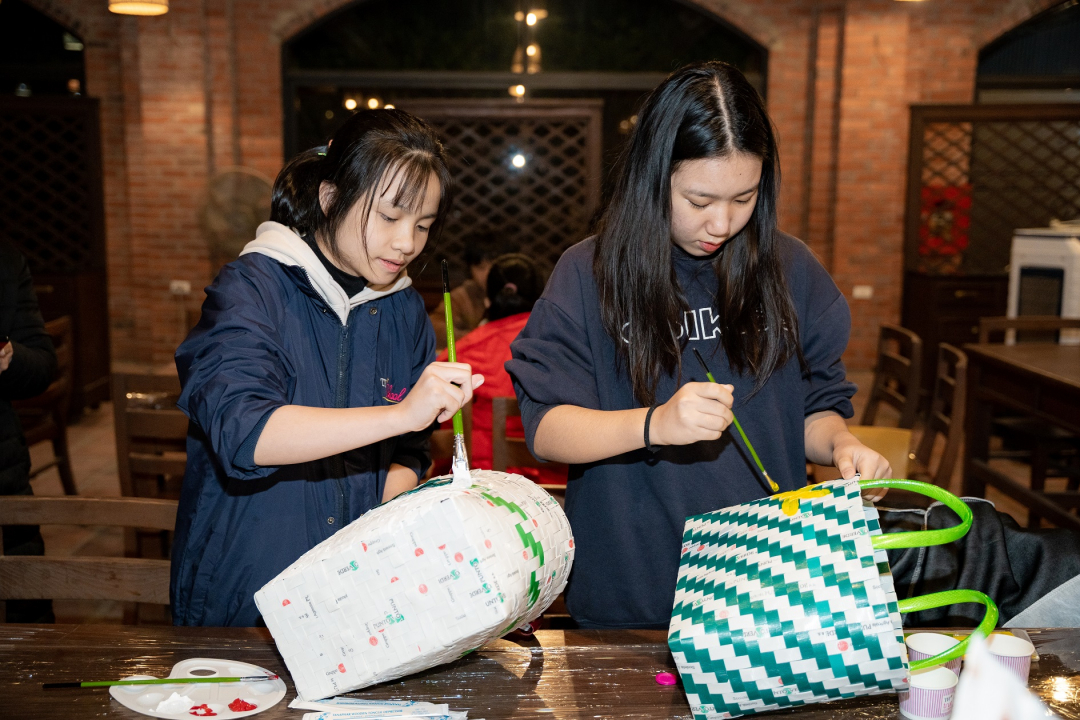 Diệu Anh (bên phải, học sinh lớp 10 TH School) hào hứng trang trí chiếc làn làm bằng dây buộc cỏ. Đây là chiếc làn bạn được các cô chú ở Trung tâm Thức ăn đan tặng.