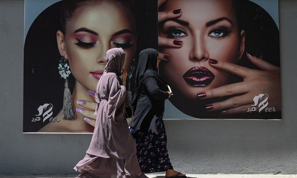 Phụ nữ Afghanistan đi qua bảng quảng cáo của một cửa hàng thời trangs ở Kabul. Ảnh: AFP.