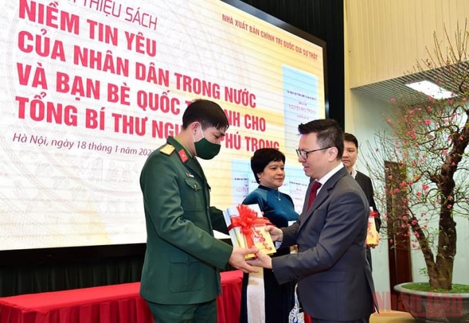 Tổng Biên tập Báo Nhân Dân Lê Quốc Minh trao tặng sách quý cho đại diện Cục Tuyên huấn, Bộ Quốc phòng.