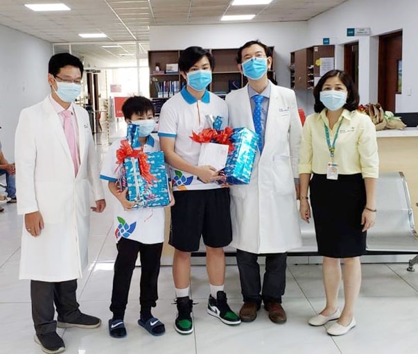 Bác sĩ Nguyễn Minh Tiến, Phó Giám đốc Bệnh viện Nhi đồng Thành phố tặng quà, áo thun lưu niệm của bệnh viện cho 'bệnh nhân 204' và anh trai sau thời gian điều trị Covid-19 tại đây. Ảnh: Hung Pham.