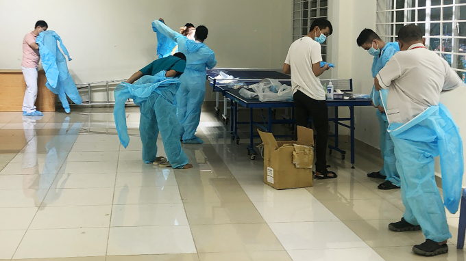 Nhân viên y tế mặc đồ bảo hộ trước khi lấy mẫu xét nghiệm sàng lọc Covid-19. Ảnh: Nguyễn Thủy.