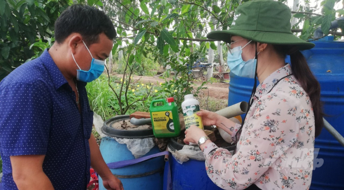 Cán bộ khuyến nông hướng dẫn hộ tham gia mô hình cách sử dụng chế phẩm vi sinh. Ảnh: H.Tiến.