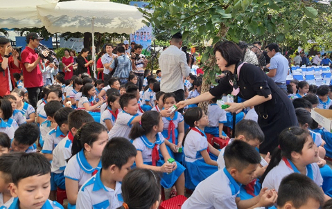 Các em học sinh trường Kim Đồng nhận những hộp sữa từ Vinamilk và các đại biểu tham dự chương trình. Ảnh: Xuân Hương.