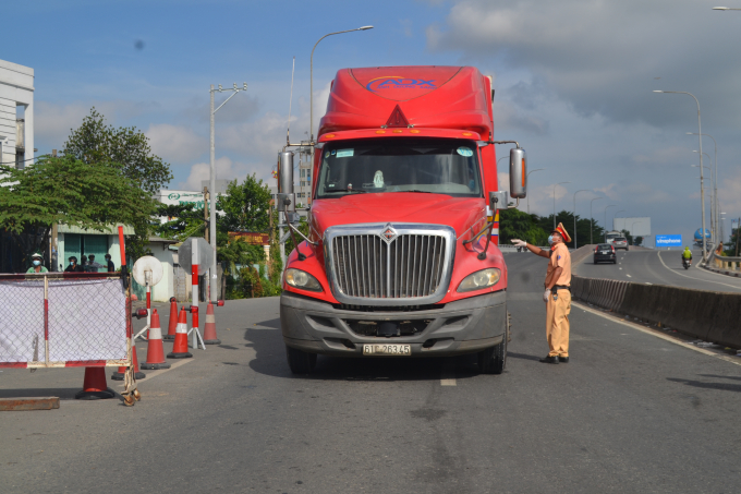 Cán bộ CSGT yêu cầu tài xế trình các thủ tục theo quy định trước khi qua chốt. Ảnh: Trần Trung.