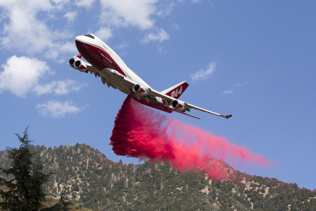Máy bay vận tải thả chất chống cháy xuống khu vực sườn đồi ở Yucaipa, California.