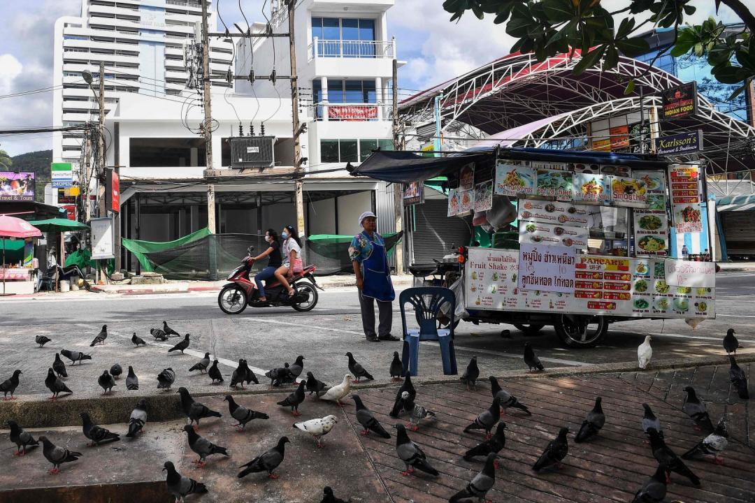 Người bán rong đồ ăn đứng đợi khách trong khi các cửa hàng đều đã đóng cửa ở thị trấn Patong.