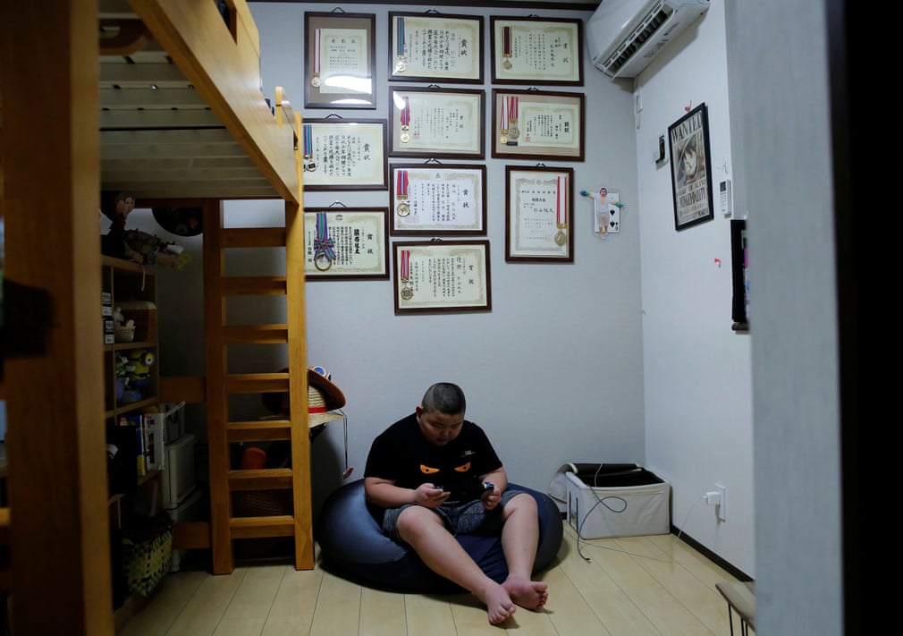 Kyuta rất thích chơi điện tử, trong ảnh em ngồi chơi ở phòng ngủ, phía trên là các bằng khen, huy chương về sumo mà em đã giành được.