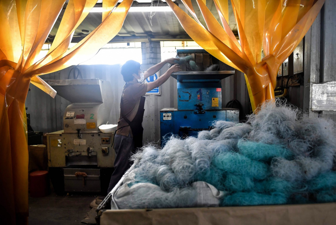 Công nhân đưa các cuộn lưới đã làm sạch vào máy nghiền.