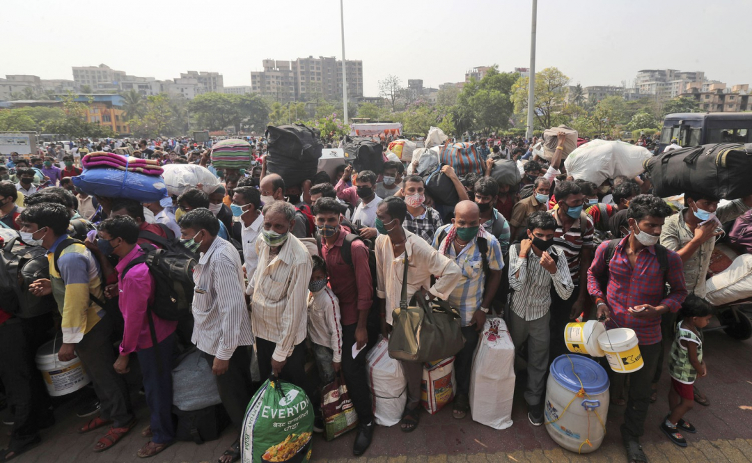 Người dân đeo mặt nạ, mang theo hành lý đứng xếp hàng chờ lên tàu tại Lokmanya Tilak Terminus ở Mumbai, Ấn Độ sau khi các biện pháp phòng ngừa Covid-19 được triển khai khiến công việc của họ bị gián đoạn.