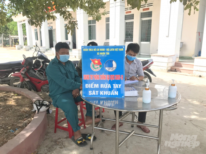 Khách đến làm việc tại UBND xã Nhơn Tân (TX An Nhơn, Bình Định) phải dừng lại rửa tay sát khuẩn, đo thân nhiệt. Ảnh: Vũ Đình Thung.