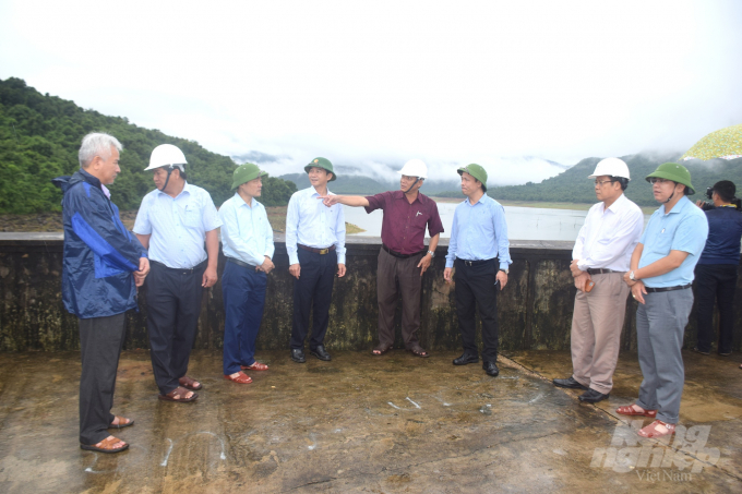Ông Nguyễn Văn Phú, Chủ tịch Công ty TNHH KTCTTL Bình Định (người mặc áo đỏ đứng giữa), báo cáo công công tác phòng chống thiên tai tại hồ Núi Một. Ảnh: Vũ Đình Thung.